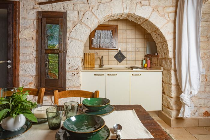 L’angolo cottura sotto l’arco in pietra e il tavolo apparecchiato
