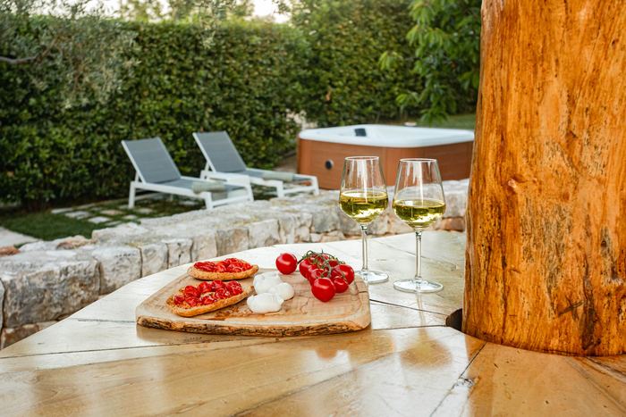 Bruschette e vino sul tavolo in legno, con la jacuzzi sullo sfondo