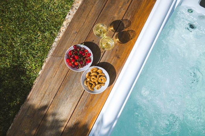 La jacuzzi vista dall’alto, con calici e frutta sul bordo in legno
