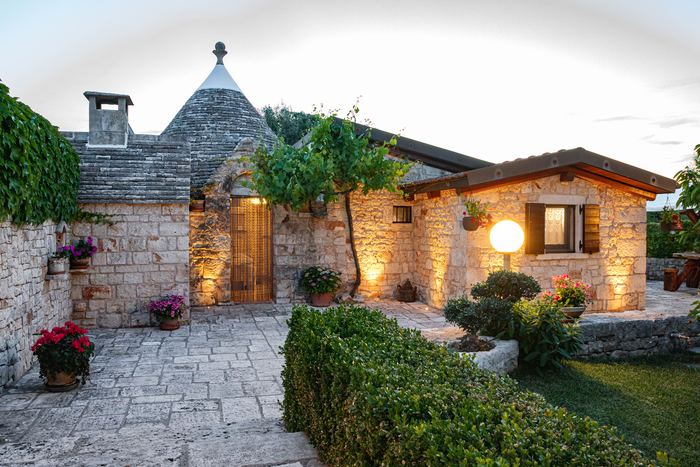 Il trullo illuminato al tramonto, con il cortile in pietra
