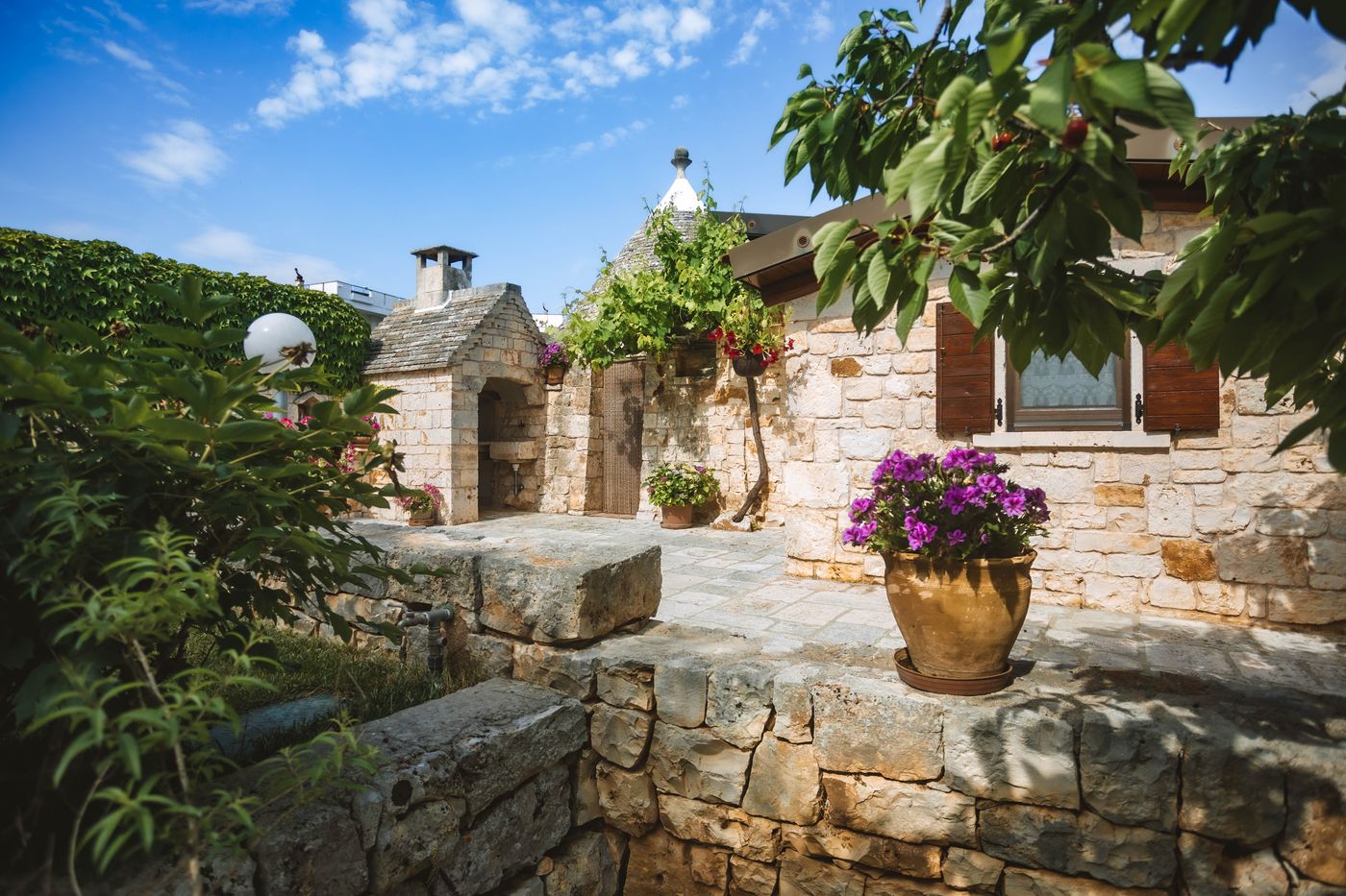 Il cortile in pietra con i vasi di fiori davanti al trullo