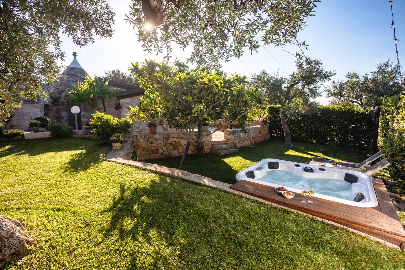Il giardino con prato, ulivi e jacuzzi, con il trullo sullo sfondo